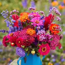 Colorful bouquet of flowers of the summer sangria bouquet in a blue vase with a blurred natural background