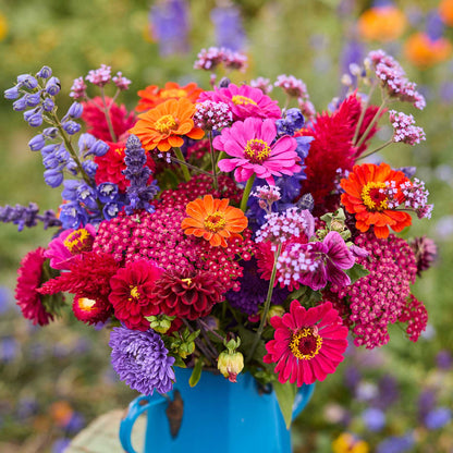 Colorful bouquet of flowers of the summer sangria bouquet in a blue vase with a blurred natural background