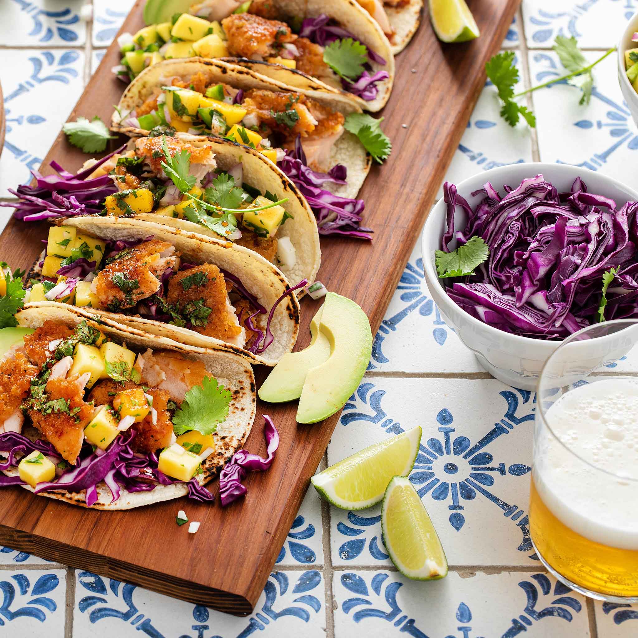 Several tacos garnished with Red Express cabbage on a tiled surface.