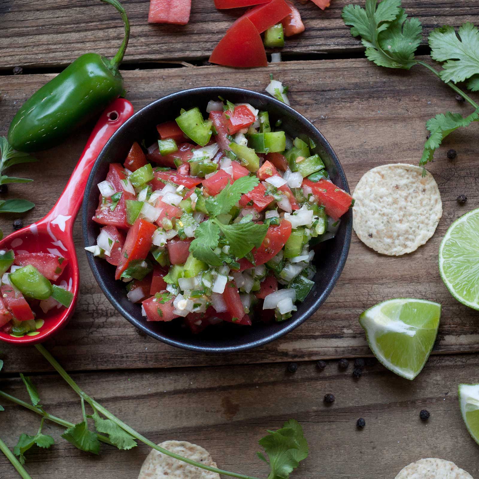 A bowl of salsa with pepper, tomatoes, and onions topped with Eagle Cilantro.