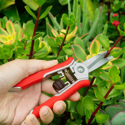 A person using Corona ComfortGel Mini Floral Snips against a green plant background