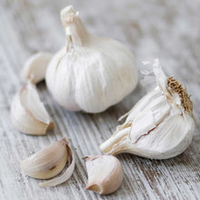 Garlic california early bulbs with white skin, cloves displayed, on a wooden surface.