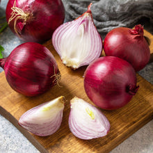 Red karmen onions on a wooden cutting board with a gray cloth background