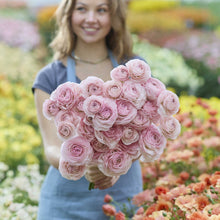 Woman holding a bouquet of pink seine ranunculus in a garden setting