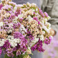 Statice pastel mix purple, pink and yellow bouquet held by person with blurred background