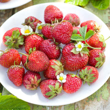 White plate with fresh quiault strawberries on a rustic wooden surface