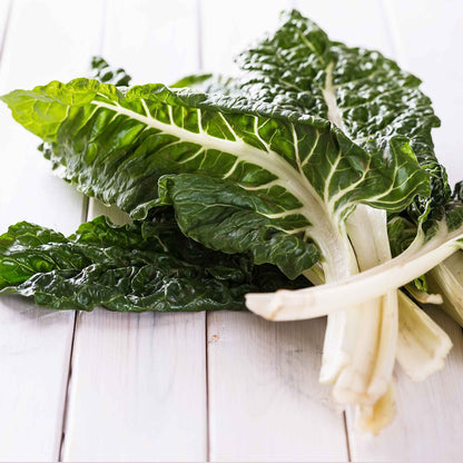 Close-up of vibrant green Fordhook Giant Swiss chard leaves with visible veins, filling the frame.