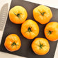 A group of ripe Azoychka tomatoes, yellow with slight red blushing, on a cutting board.