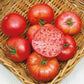 A group of ripe, large red Mortgage Lifter tomatoes with a green stem and one sliced on top.