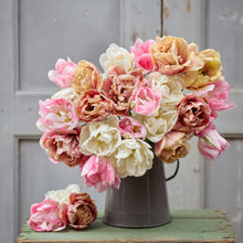 A person holding a pink, orange, and yellow bouquet from the antique cameo tulip bundle