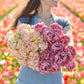 A person holding a pink and pale yellow bouquet from the beachberry and pink mist tulip bundle