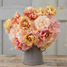 Bouquet of pink and yellow tulips from the double rose bundle in a gray vase on a wooden surface with a light gray background.