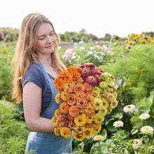 A person holding a bouquet of the zinnia bundle queeny series in a garden setting