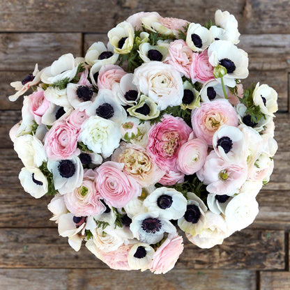 A bouquet of Paris in Spring anemone and ranunculus flowers with a mix of pink, white, and beige petals.